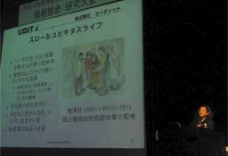 「スローなユビキタスライフ」という内容を写したステージ上で話す関根先生